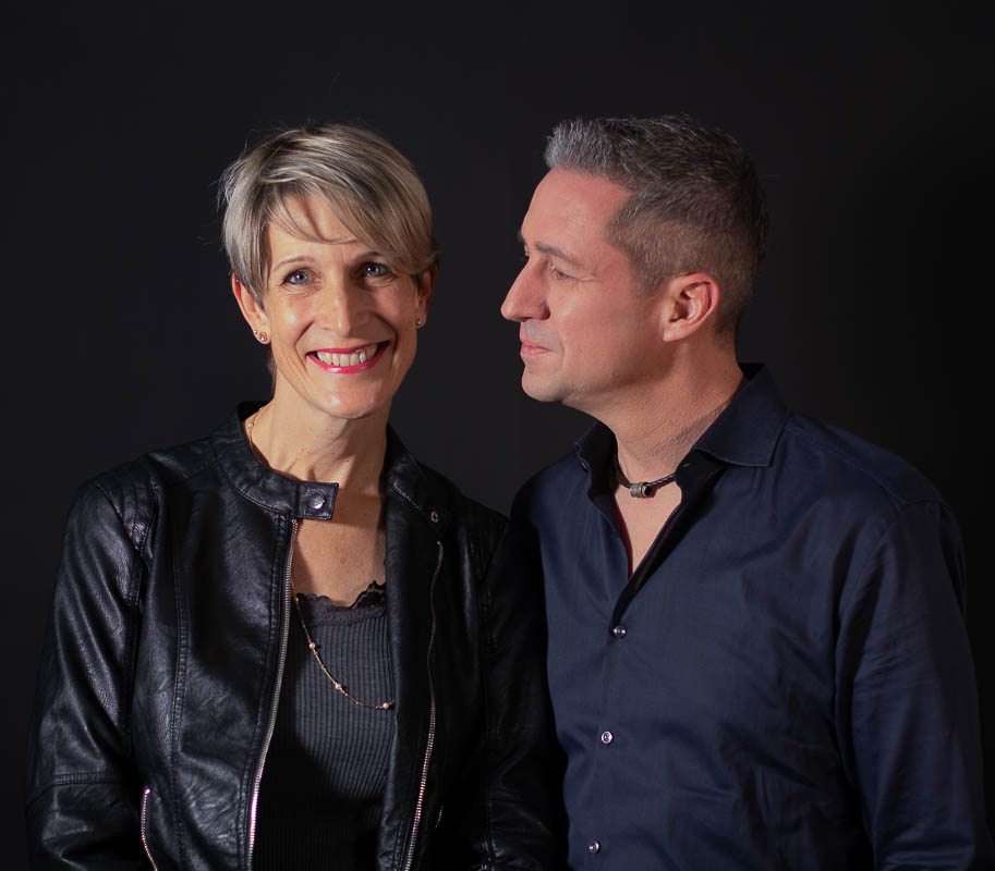 Frau lächelt in Kamera, Mann schaut sie an